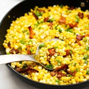 Scooping out pan fried corn kernels and bacon