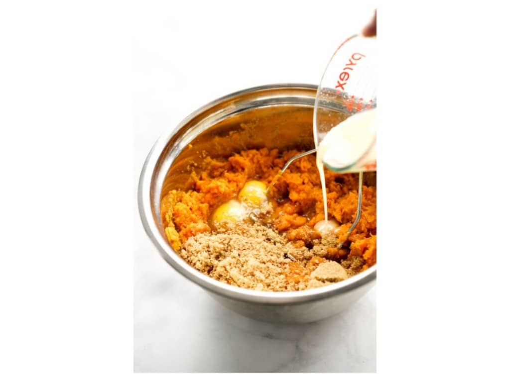 Adding brown sugar, milk and eggs to mashed sweet potato mixture in a bowl