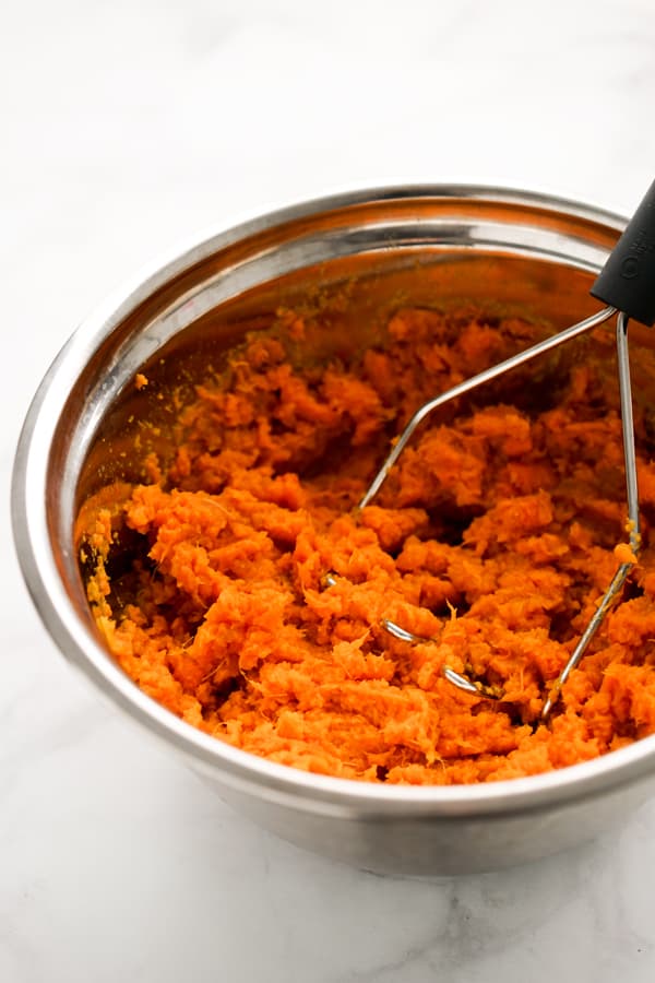 Mashing sweet potatoes in a bowl