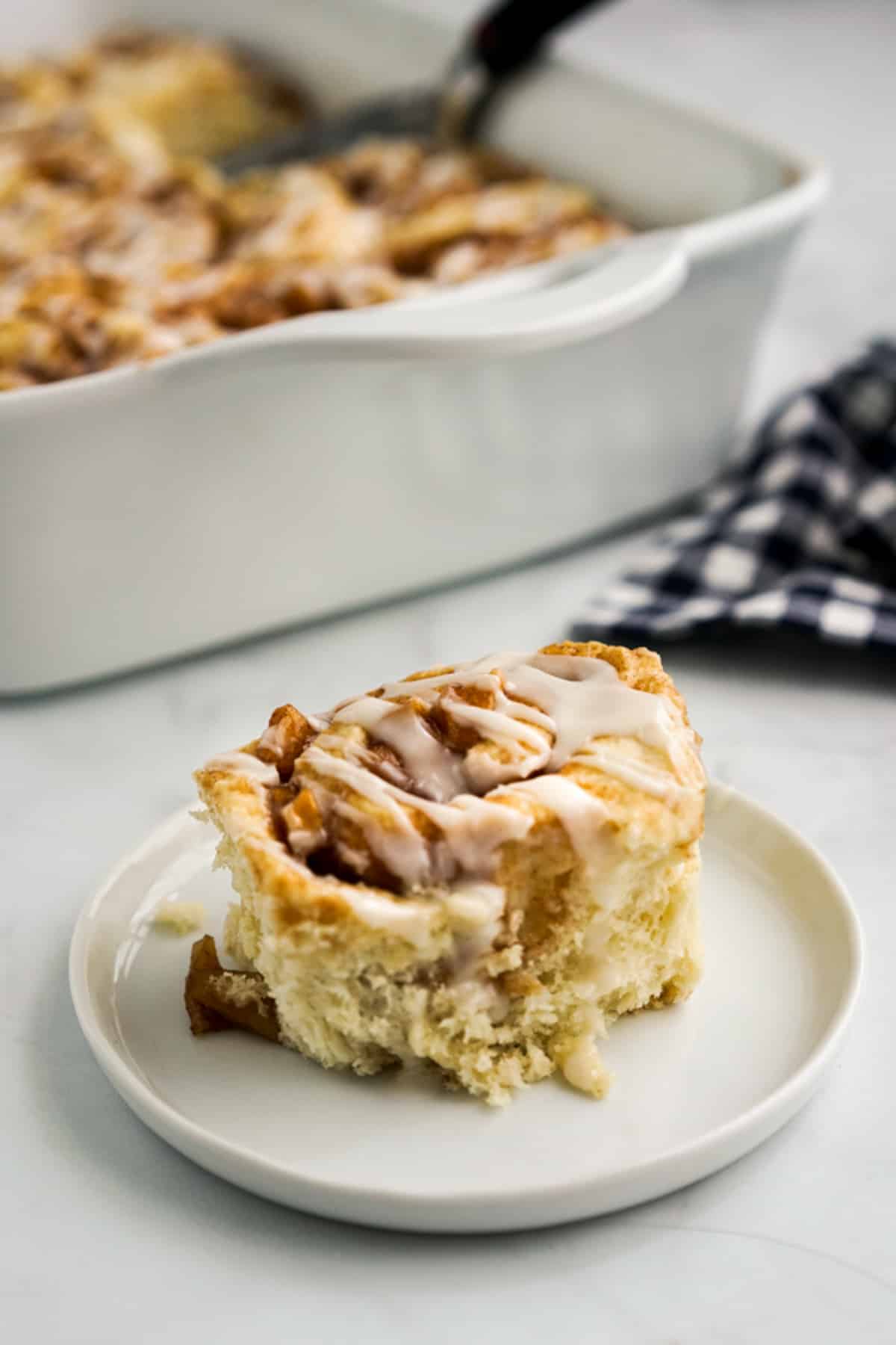 A plate of one cinnamon roll with apple pie filling