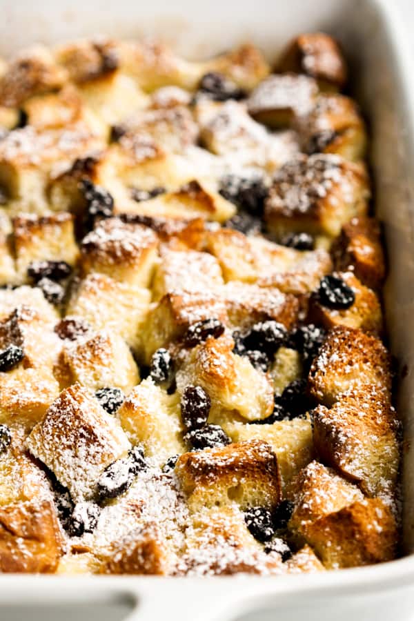 Closeup of bread pudding in a rectangular baking dish topped with powdered sugar