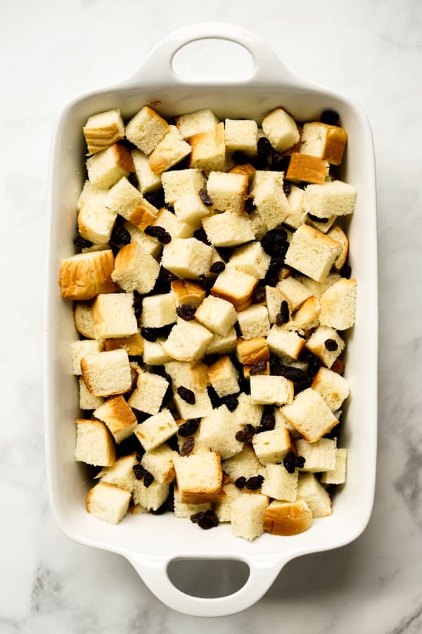 Cubed brioche bread and raisins in rectangular casserole