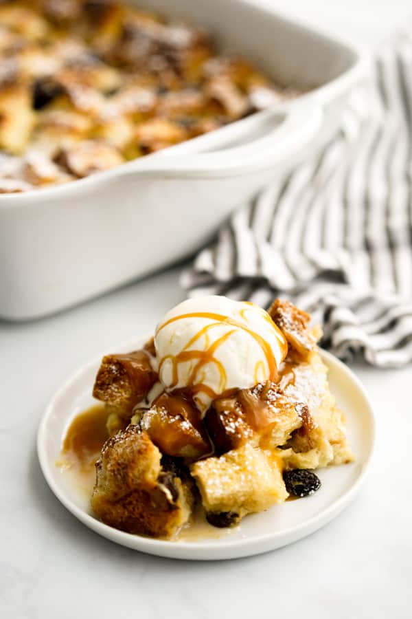 A plate of bread pudding topped with vanilla ice cream and caramel sauce