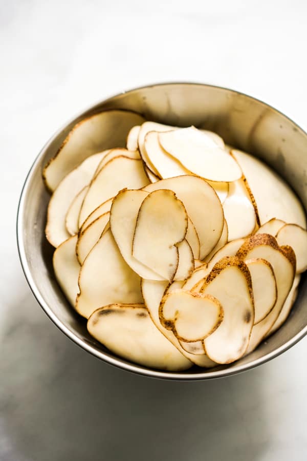 Thinly sliced russet potatoes in a bowl