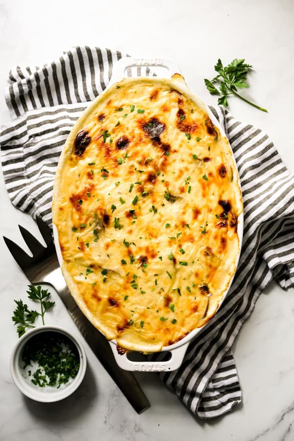 Top down view of a oval casserole of baked potato and ham au gratin