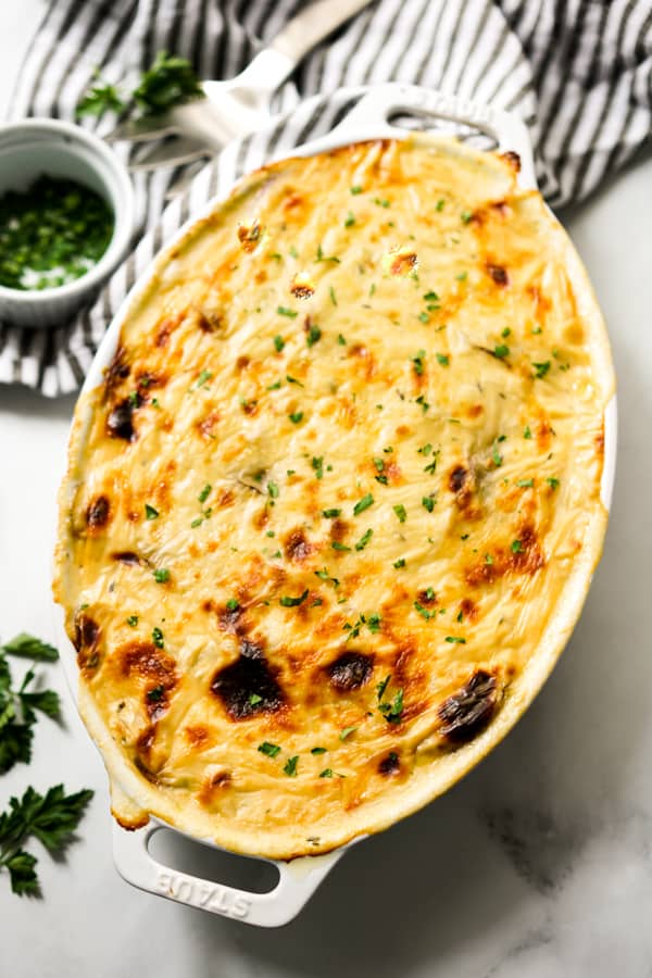 An oval casserole dish of cheesy potatoes