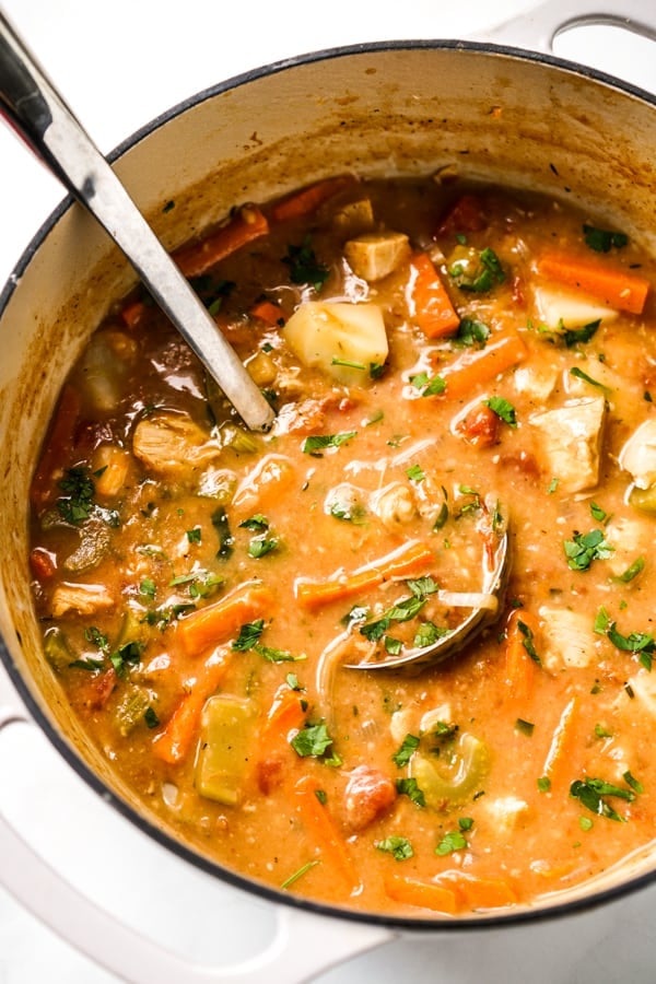 A large pot of turkey stew with ladle in it