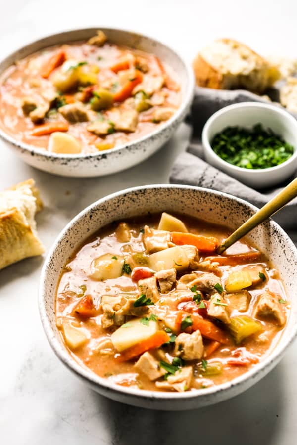 Two bowls of stew made with leftover turkey, tomatoes, carrots and celery