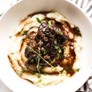 A bowl of mashed potatoes topped with red wine braised short ribs