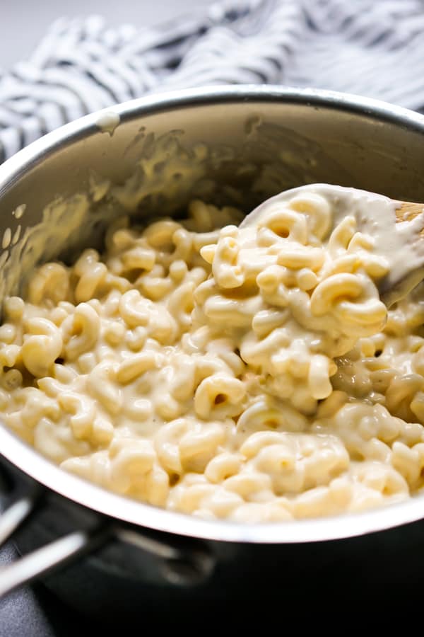 Stirring gouda macaroni and cheese in a pot with a wooden spatula