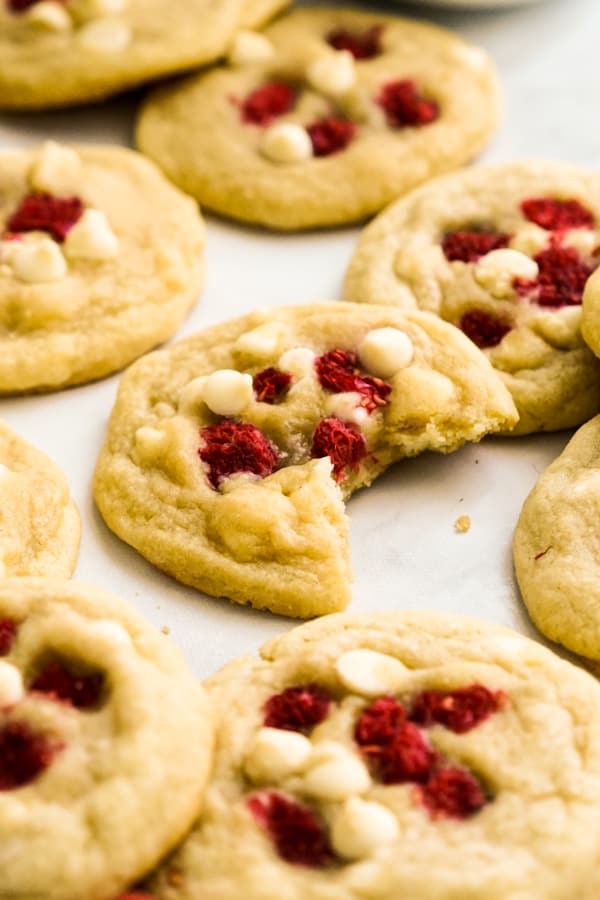 A half eaten cookie topped with raspberries and white chips