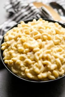 A bowl of creamy mac and cheese with kitchen towel and spatulas in the background