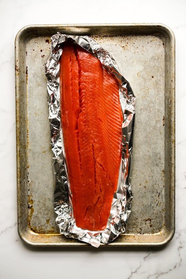 Raw salmon on aluminum foil on baking sheet