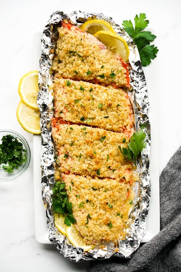 Top down view of Panko Crusted Salmon on a rectangular plate with lemon slices and parsley around it.