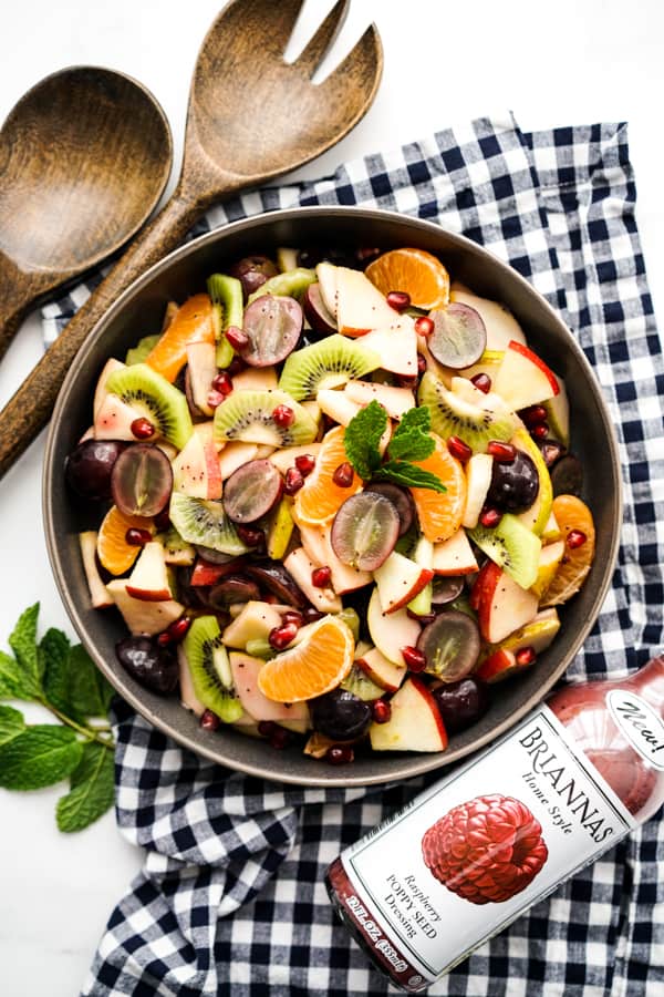 Top down view of a bowl of fruit salad with Raspberry Poppyseed Dressing on the side