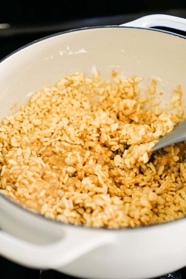 Adding rice krispie cereal into a pot of peanut butter sauce