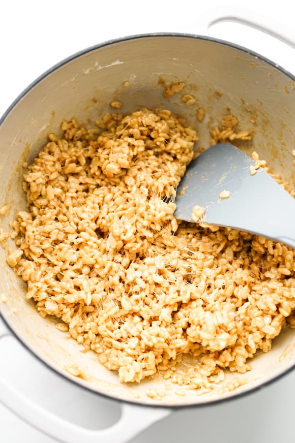 Mixing peanut butter along with rice krispies cereal in a large pot