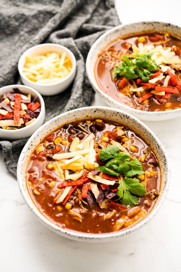 Loaded chicken taco soup topped with tortilla strips, cheese and cilantro