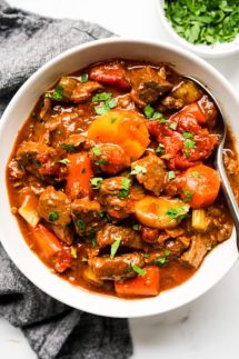 A bowl of hearty chunky beef stew with tomatoes, carrots and potatoes