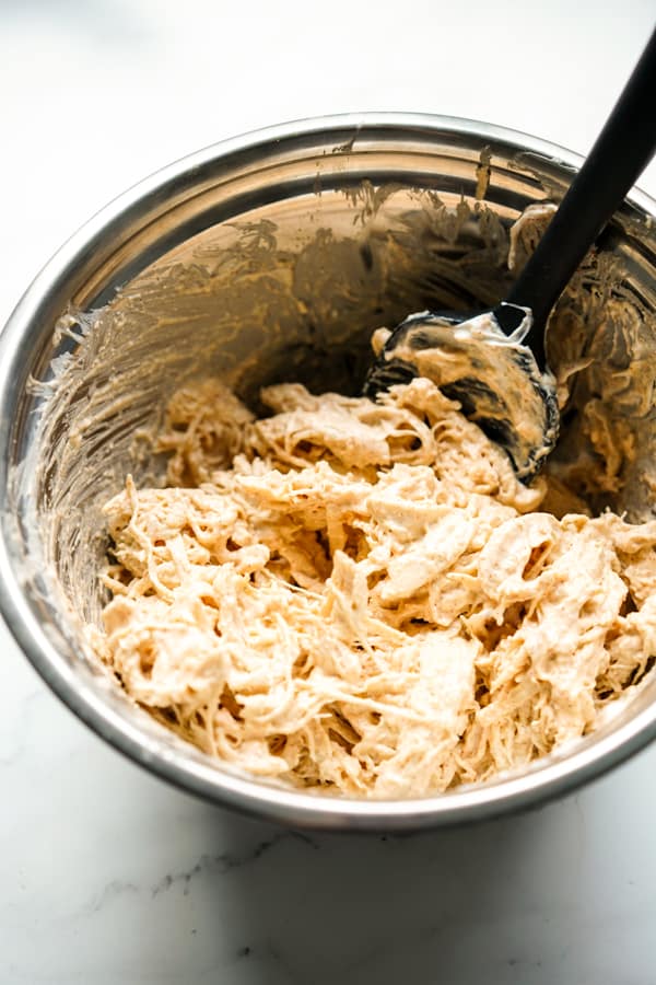 shredded chicken breast combined with sour cream and seasoning in a bowl