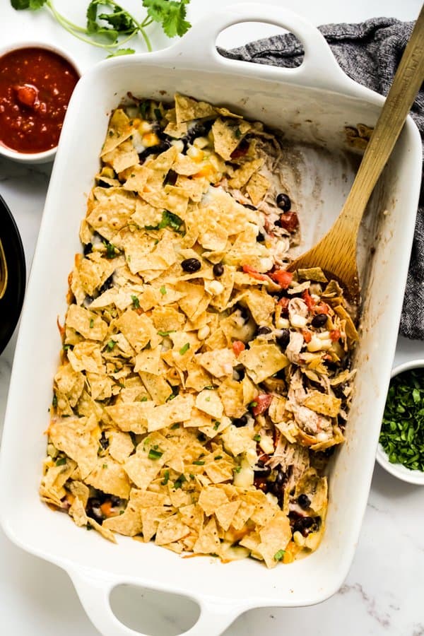 Digging into a Mexican casserole topped with tortilla chips, salsa on the side