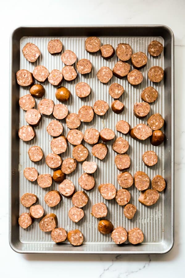 Coin shaped sausage spread out on a large sheet pan