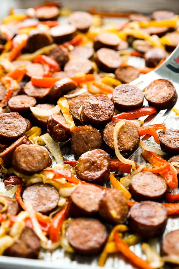 Sausage, red and orange bell peppers, and onions on sheet pan.