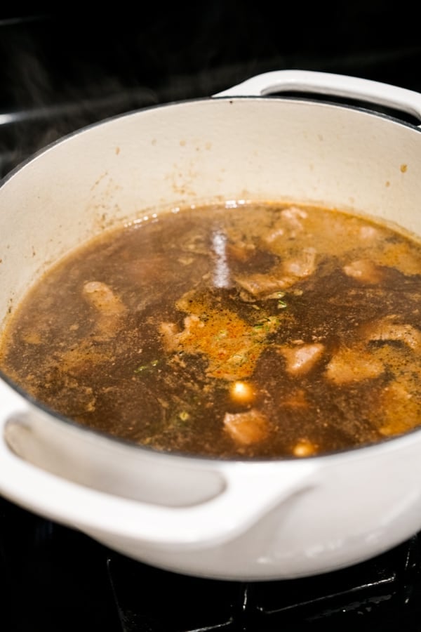 Beef broth with spices and beef chuck in a Dutch oven on the stovetop