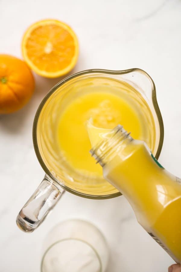 Adding orange juice to a jug