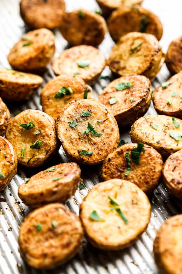 Roasted crispy halved baby potatoes on a sheet pan