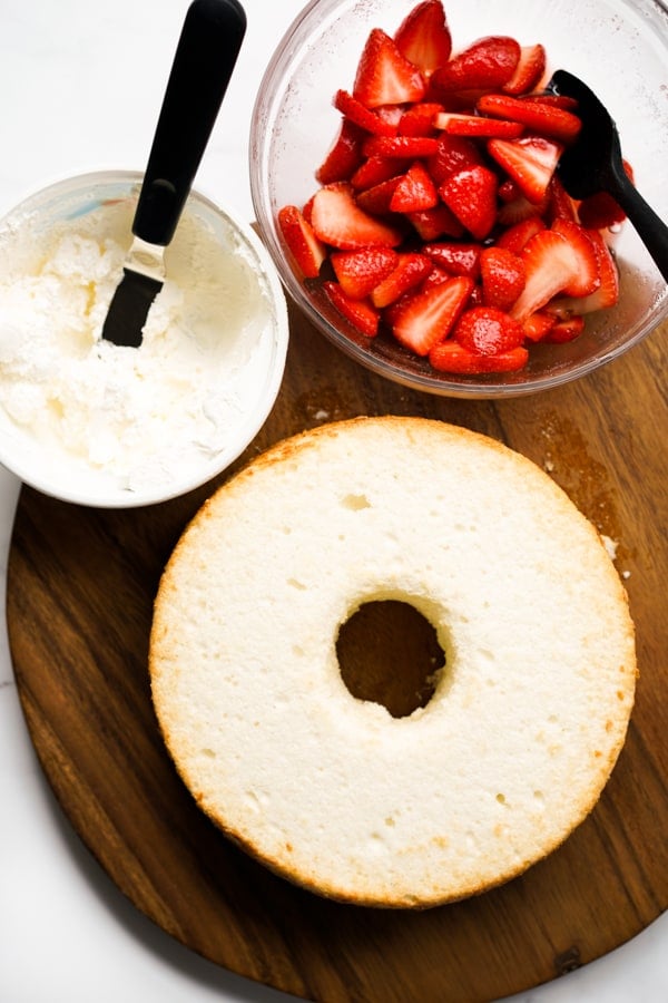 Angel food cake, a tub of cool whip, and a bowl of strawberries