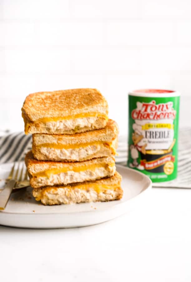 A stack of tuna melt grilled cheese with Tony Chachere's seasoning next to it