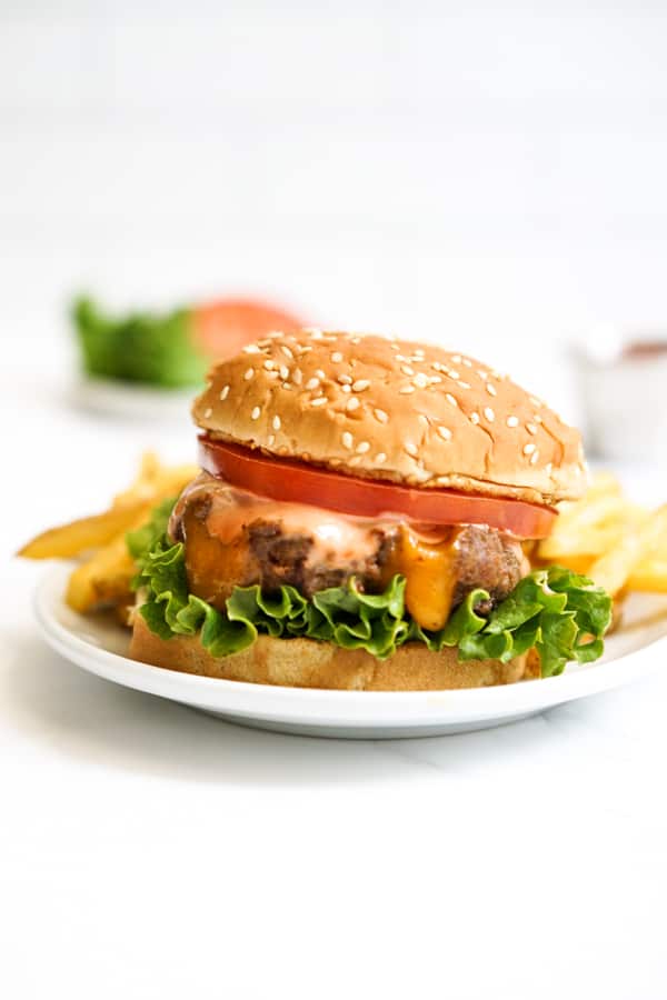 Cheese stuffed burger patties on a bun with lettuce and tomatoes