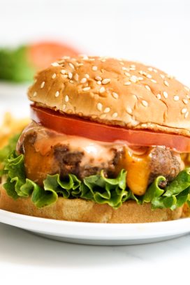 Burger with a cheese stuffed patty, lettuce, tomatoes and sauce.
