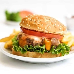 Burger with a cheese stuffed patty, lettuce, tomatoes and sauce.