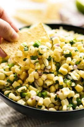 Dipping into a bowl of corn salsa with a corn chip