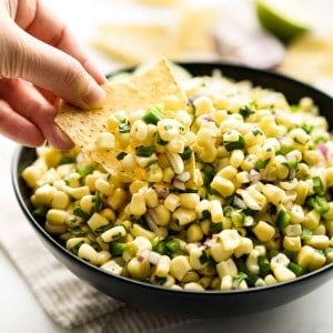 Dipping into a bowl of corn salsa with a corn chip