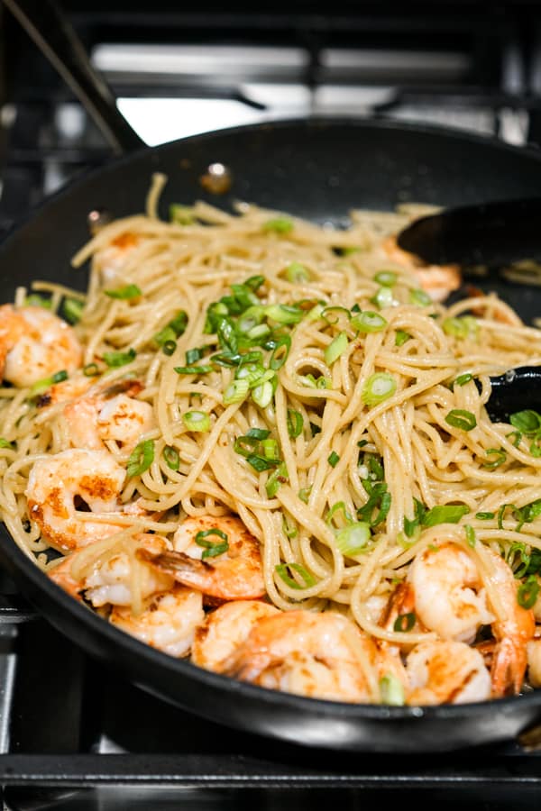 Noodles, shrimp, and green onions in a skillet