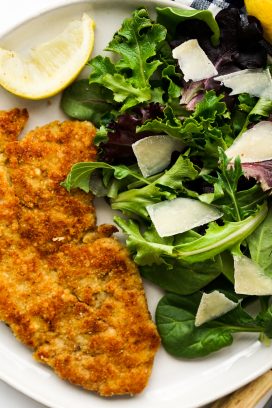a plate of pork chop Milanese with a side salad
