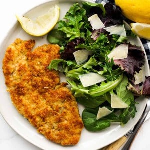 a plate of pork chop Milanese with a side salad