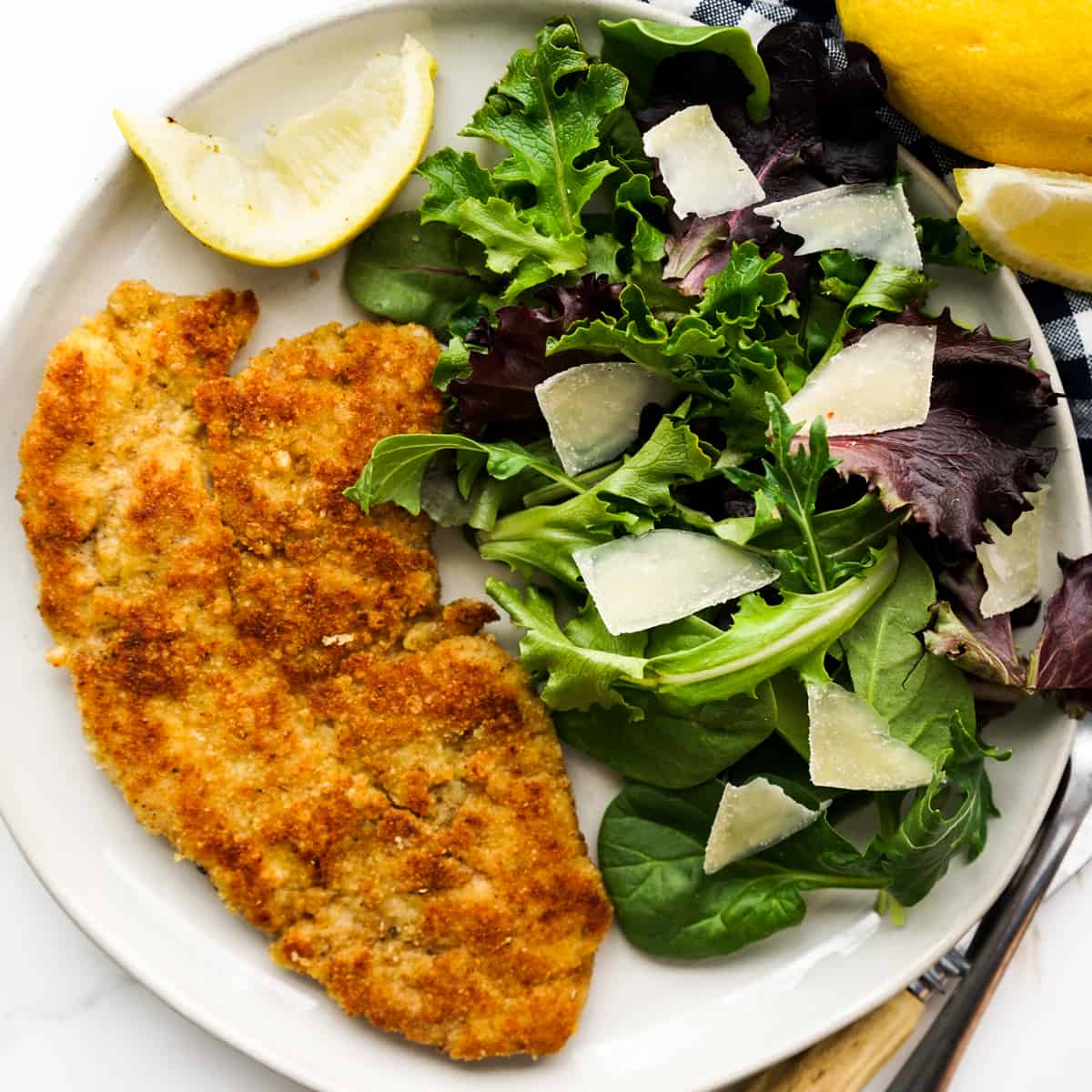 a plate of pork chop Milanese with a side salad