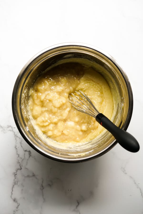 mashed bananas with wet mixture in a mixing bowl