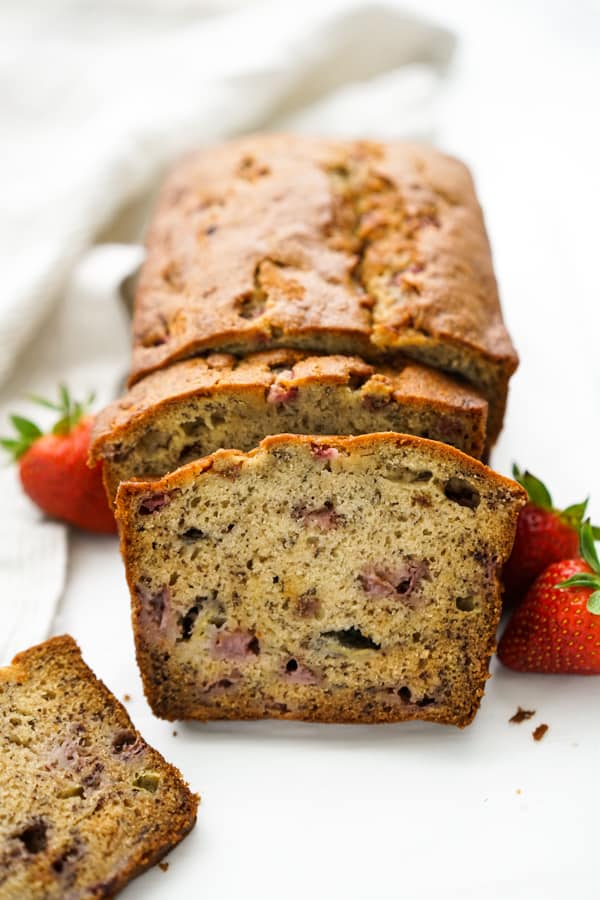 A loaf of strawberry banana bread with a few slices cut up
