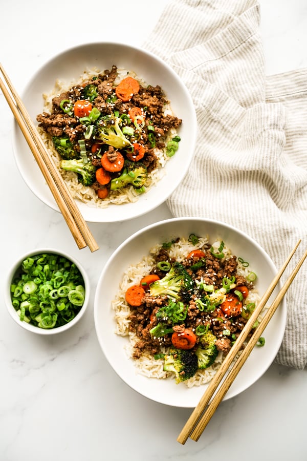 Top down view of two bowls of ground beef stir with vegetables fry over rice