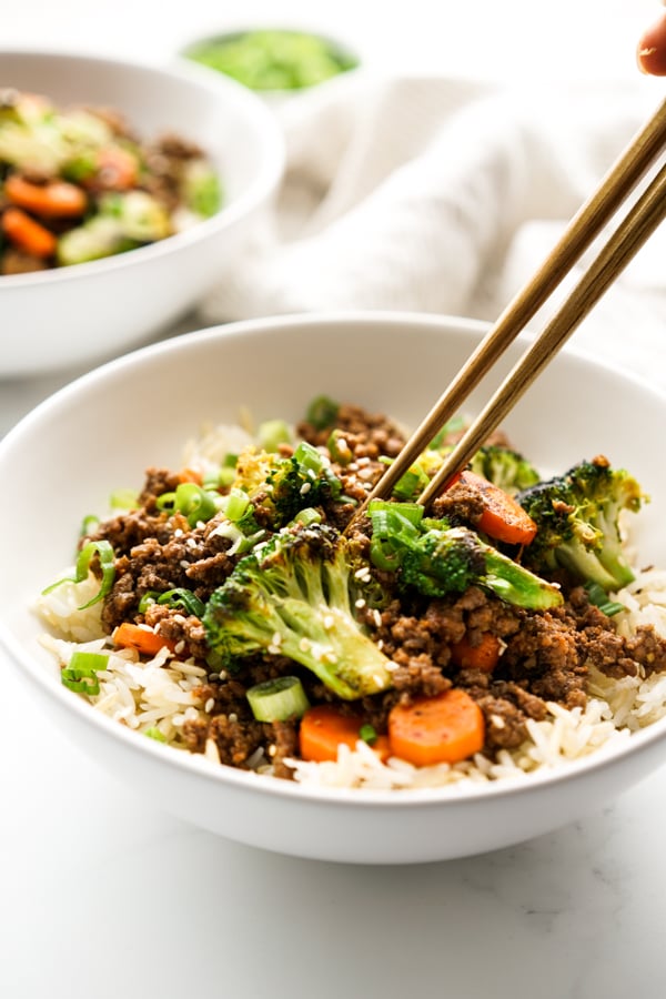 Chopsticks picking up items from Korean Ground beef stir fry in a bowl