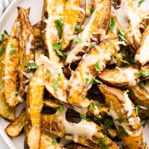 Closeup of Cheesy Potato wedges topped with chopped parsley