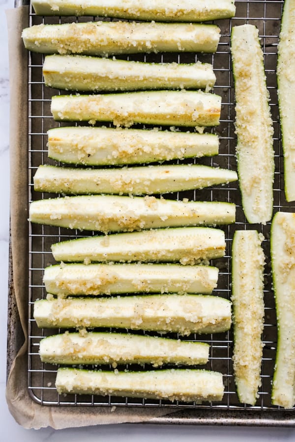 unbaked zucchini spears topped with garlic and parmesan on baking rack