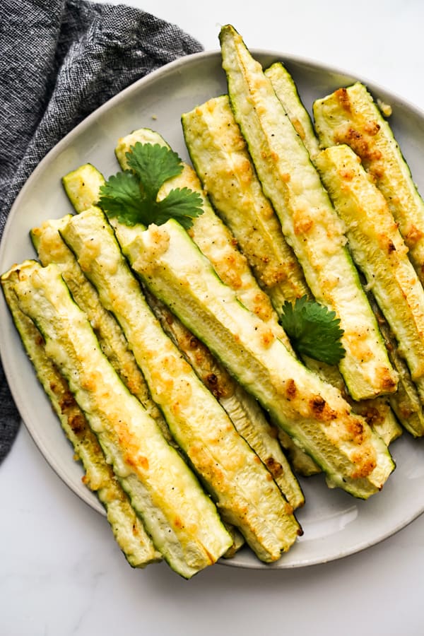 Roasted Zucchini spears baked with garlic and parmesan on a round plate