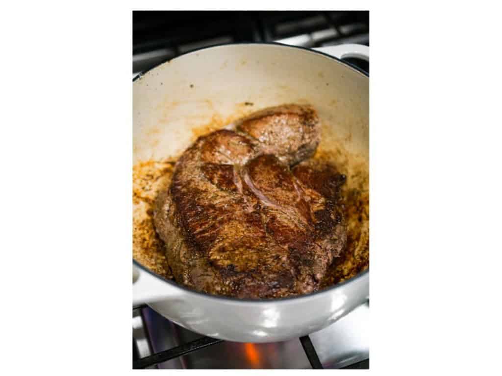 Sauteing a large piece of beef chuck in the Dutch oven until golden brown