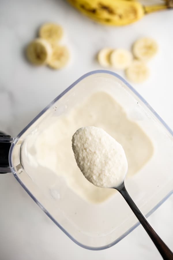 Scooping a spoonful of banana milkshake from blender